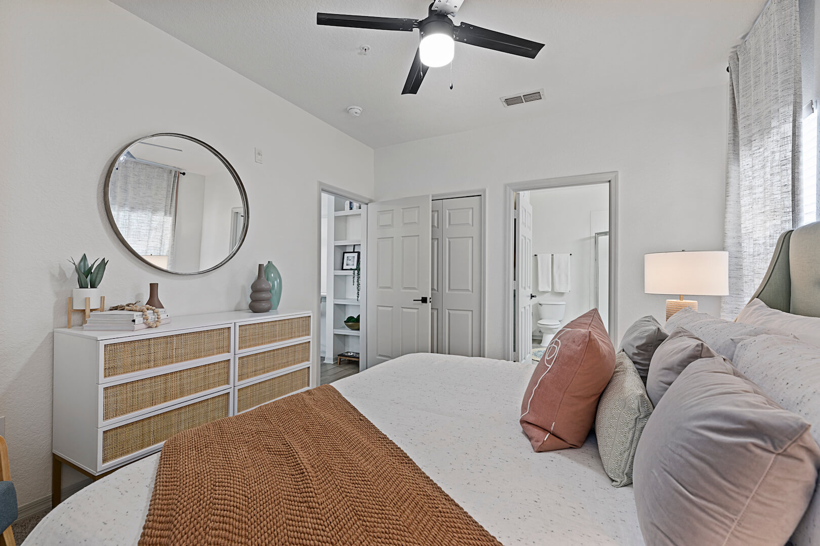 model bedroom with ceiling fan and opens to bathroom